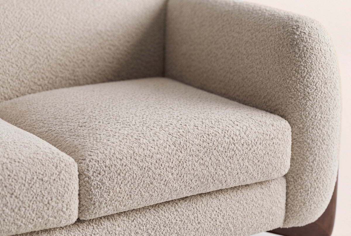 Close-up of the almond boucle seat cushion, the rounded arm and the back of the Greccio loveseat
