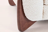 Close-up of a solid birch wedge leg in a walnut-brown stain under the beige boucle arm
