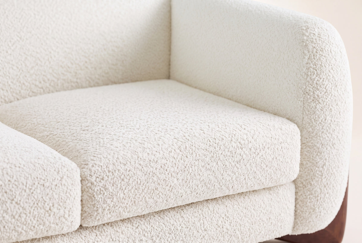 Close-up of the beige boucle seat cushion, the rounded arm and the back of the Greccio loveseat
