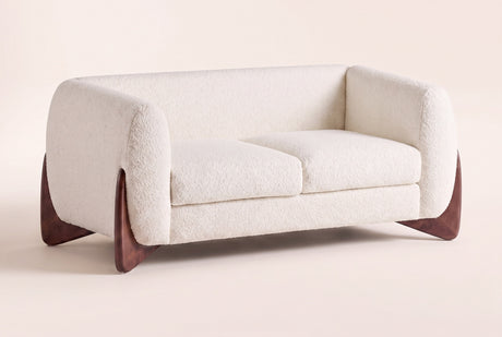 Greccio boucle loveseat in beige, three-quarter view on a warm off-white backdrop