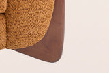 Close-up of a solid birch wedge leg in a walnut-brown stain under the caramel boucle arm