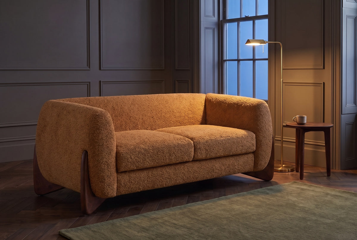 Greccio boucle loveseat in caramel in a dark panelled townhouse sitting room at dusk, a brass floor lamp lit beside it