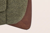 Close-up of a solid birch wedge leg in a walnut-brown stain under the olive green boucle arm