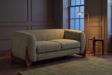 Greccio boucle loveseat in olive green in a dark panelled townhouse sitting room at dusk, a brass floor lamp lit beside it