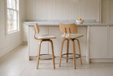 Two Gressoney counter stools in Beige / Natural, one in profile and one from behind, at a white island with a marble top in a panelled Charlottetown kitchen