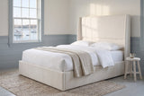 Greve wingback bed in a bedroom with blue-grey wainscot, a braided rug and a sash window onto a harbour with sailboats