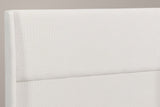 Close-up of the Greve headboard: the rounded top of a wing, the fine beige chenille weave and the one channel line
