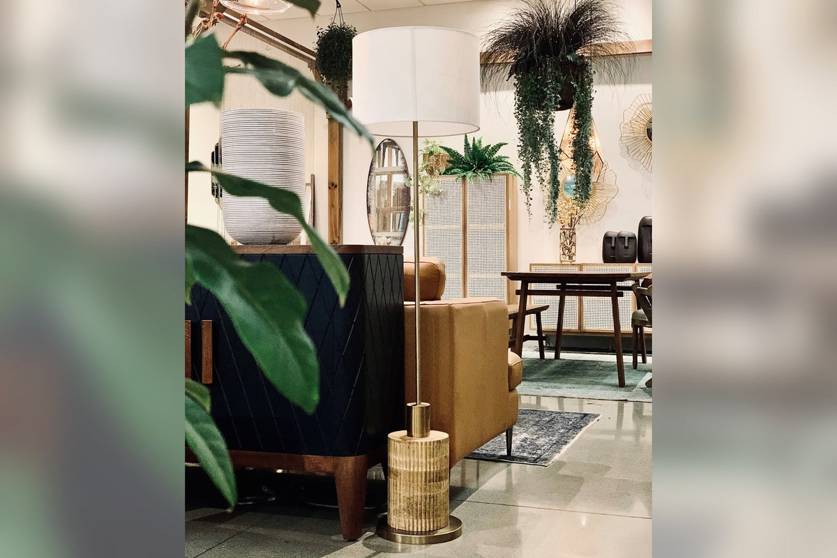 Hadrian floor lamp with reeded wood base beside a leather chair in a styled room