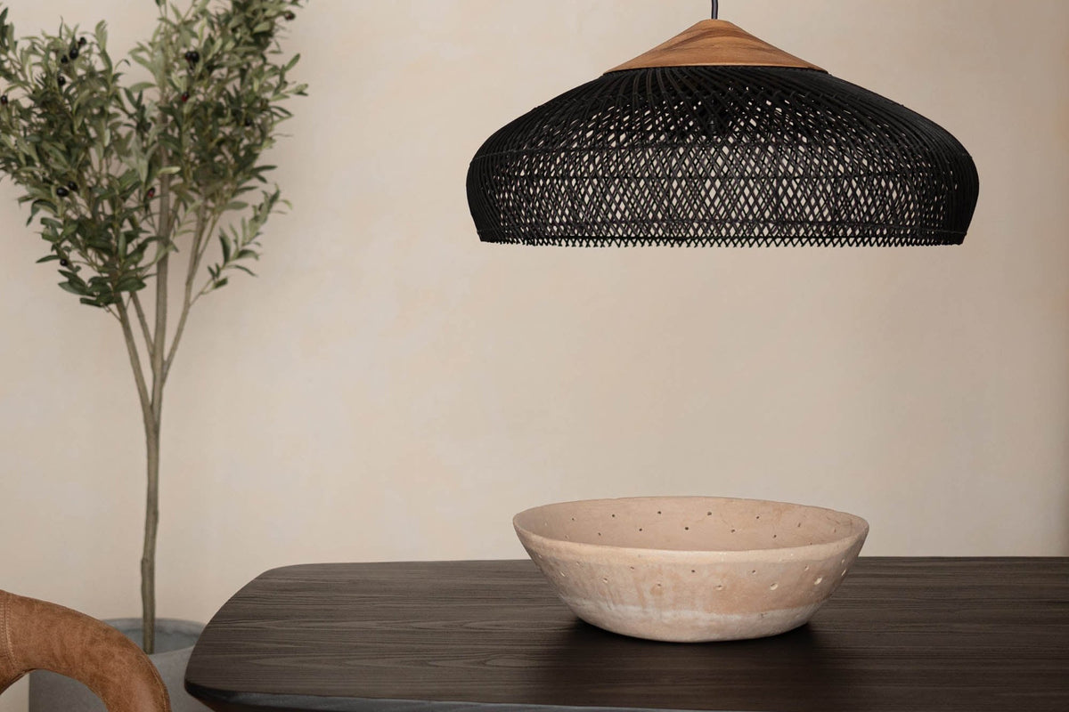 Halden black rattan pendant light hanging over a dark wood dining table
