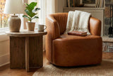Hollis Saddle leather swivel chair in a reading nook beside bookshelves and a window