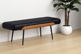 Iver black faux leather bench against a white wall beside a potted plant