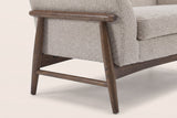 Close-up of the wooden side frame: a round arm rail, two splayed tapered legs, a low stretcher and bolt caps