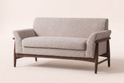 Jesi flared-arm loveseat in almond boucle on a walnut-finish wood frame, three-quarter view on a warm cream studio backdrop