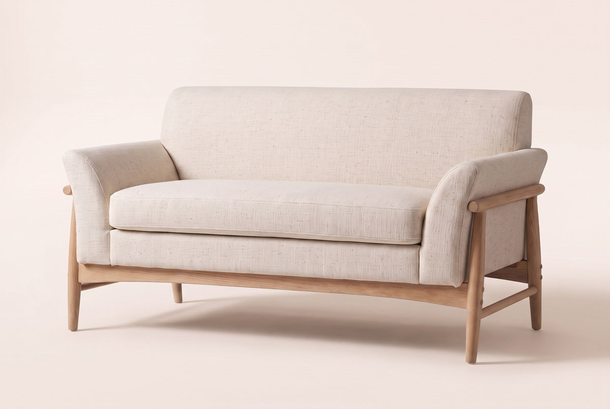 Jesi flared-arm loveseat in beige woven fabric on a natural-finish wood frame, three-quarter view on a warm cream studio backdrop