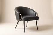 Kenna accent chair in Vintage Charcoal, three-quarter view on a warm off-white studio backdrop: a rounded barrel back wrappin