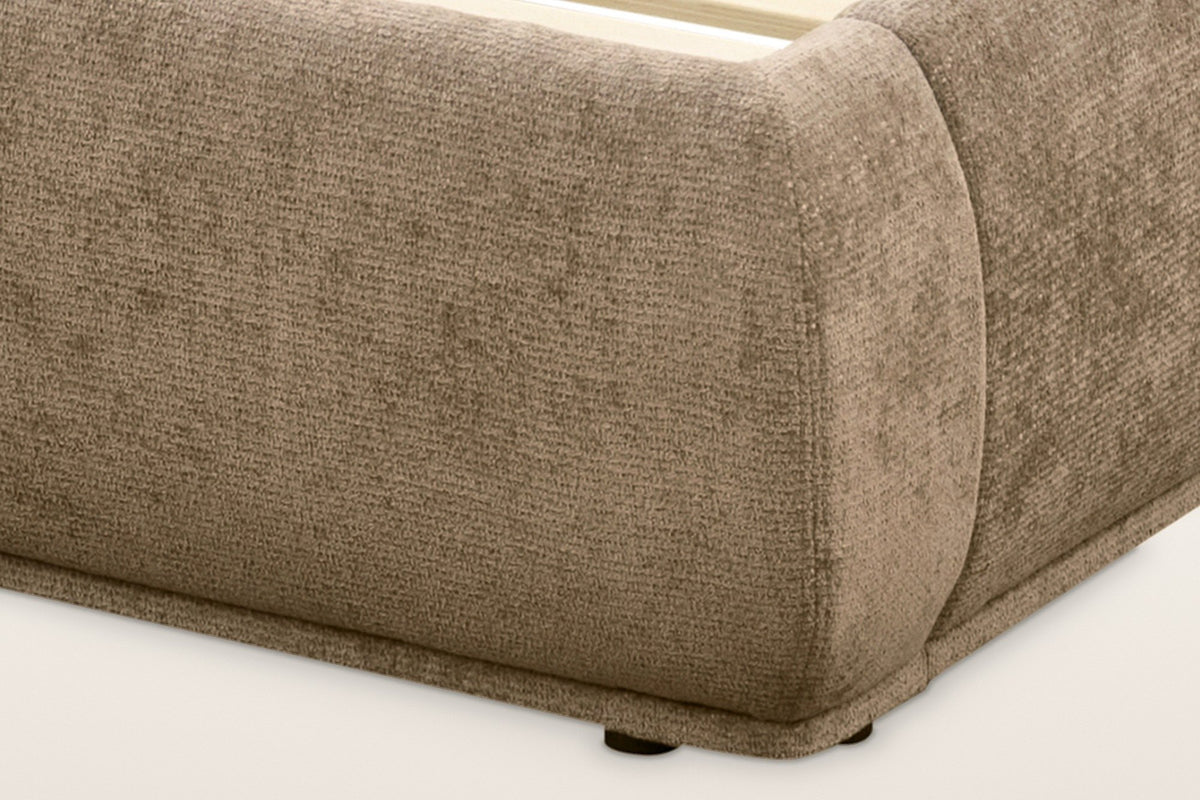 The rounded foot corner of the Labro bed: the padded rail end, the slim upholstered plinth and a small dark glide