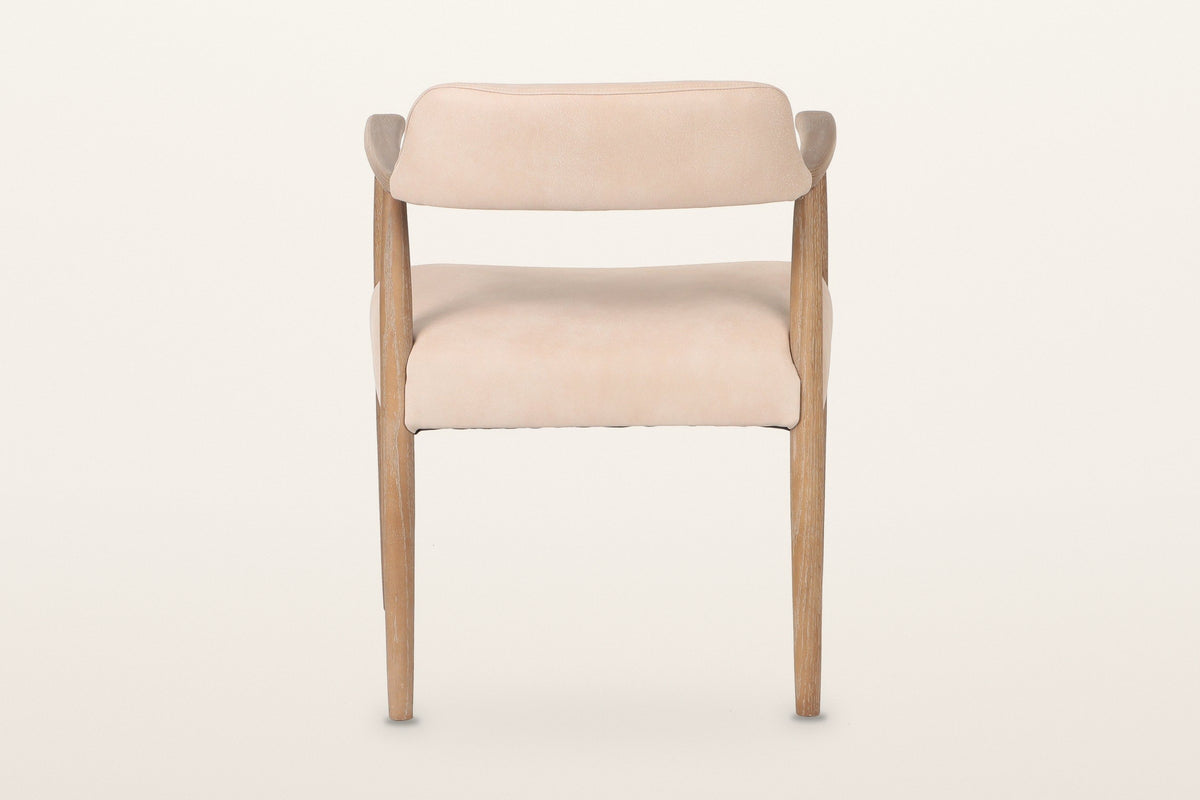 Back of the Laigueglia dining armchair in Beige leather on a warm white studio backdrop: the band is covered on the back too