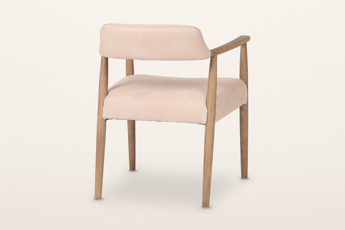 Laigueglia dining armchair in Beige leather from the back at three-quarter on a warm white studio backdrop