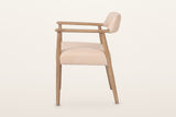Laigueglia dining armchair in Beige leather, side view on a warm white studio backdrop: the level arm