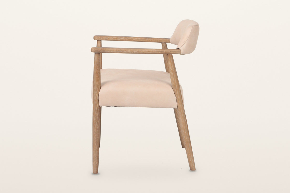 Laigueglia dining armchair in Beige leather, side view on a warm white studio backdrop: the level arm