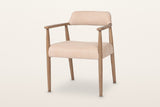 Laigueglia dining armchair in Beige leather, three-quarter view on a warm white studio backdrop: a low curved back band
