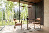 Two Laigueglia armchairs in Brown leather facing across a black marble pedestal table in a Bragg Creek house