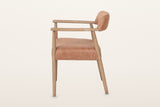 Laigueglia dining armchair in Brown leather, side view on a warm white studio backdrop