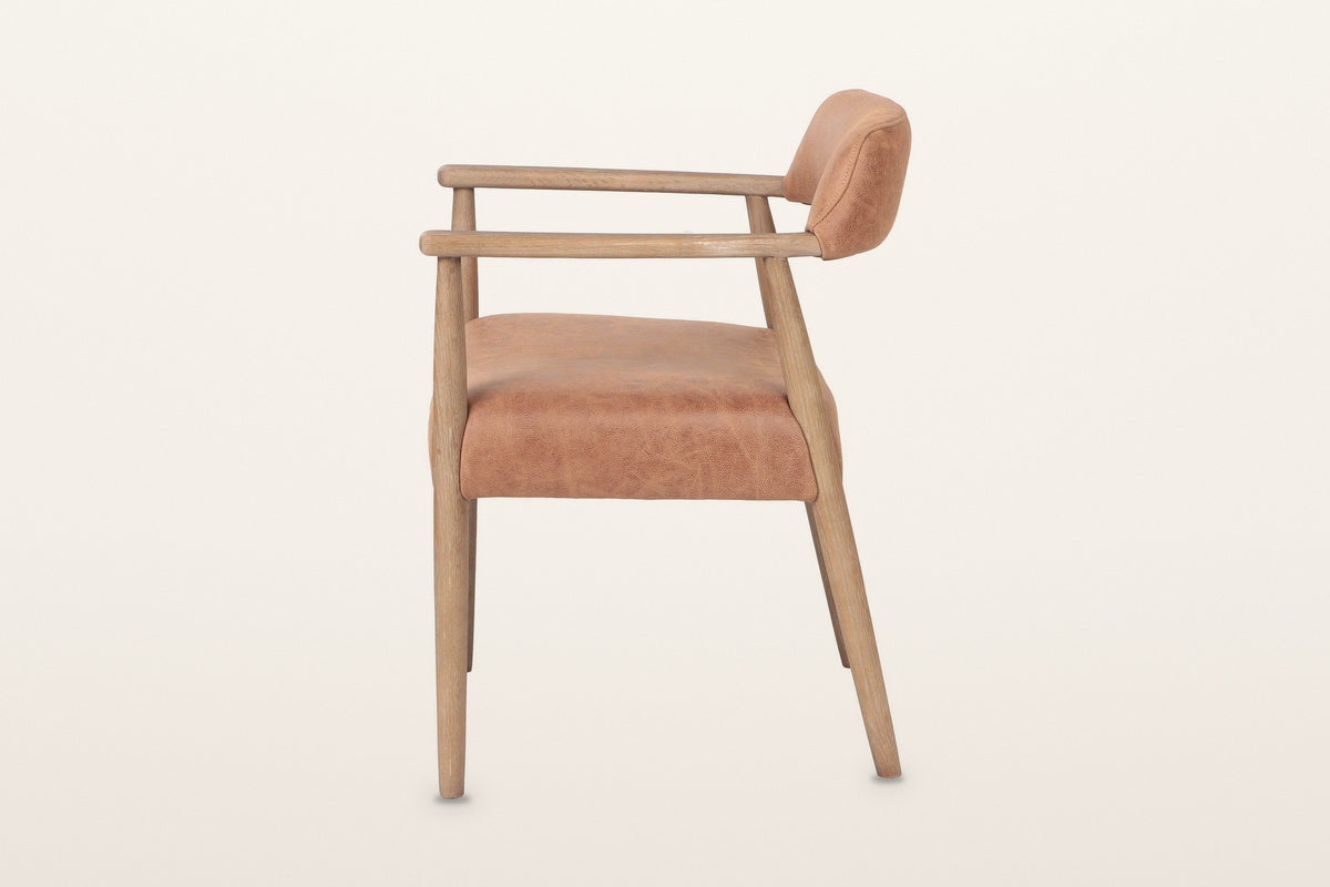 Laigueglia dining armchair in Brown leather, side view on a warm white studio backdrop