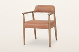 Laigueglia dining armchair in Brown leather, three-quarter view on a warm white studio backdrop