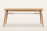 Larino dining table in Natural, front view on a warm white studio backdrop: the centre rod and its Y at each end