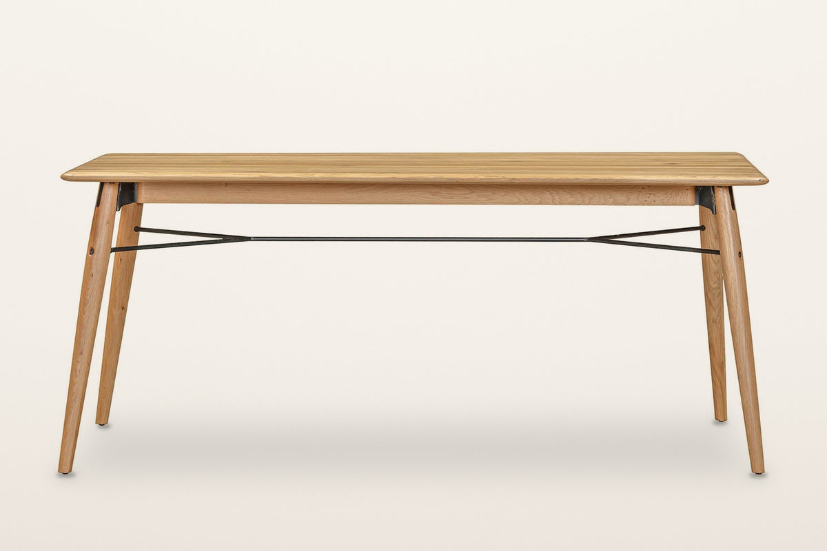 Larino dining table in Natural, front view on a warm white studio backdrop: the centre rod and its Y at each end