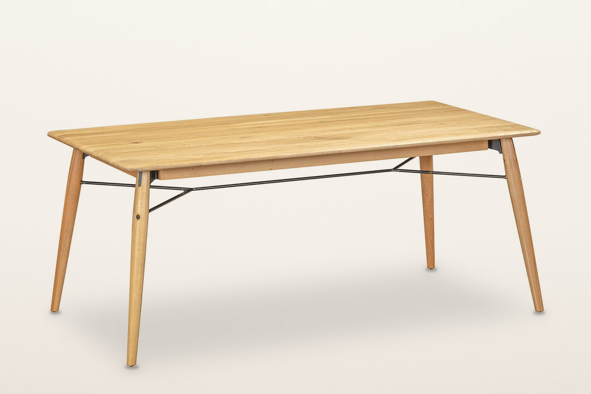 Larino oak dining table in Natural, three-quarter view on a warm white studio backdrop: four splayed legs and thin black rods