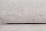 Close-up of the Lavagna ottoman in Beige: a pillow's rounded edge and its one fine seam over the pillow below