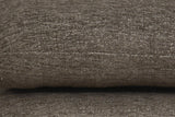 Close-up of the Lavagna ottoman in Brown: a pillow's rounded edge and its one fine seam over the pillow below