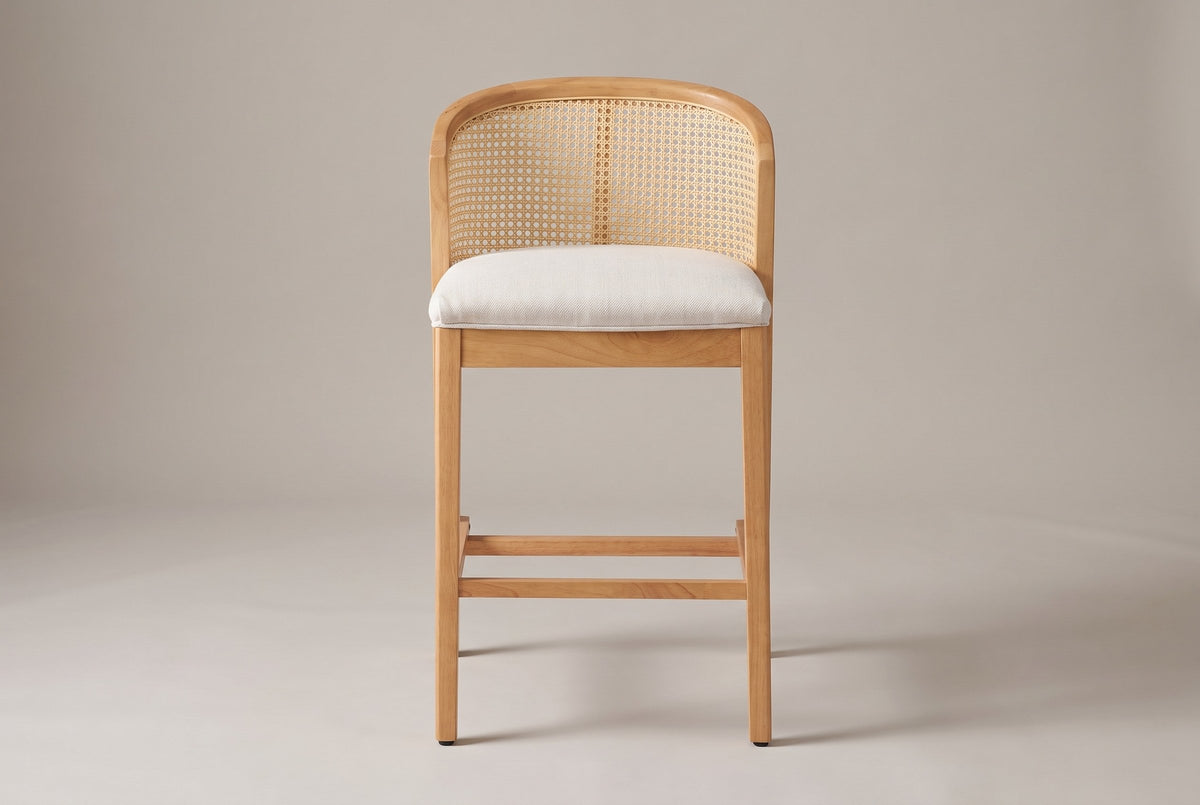 Lazise counter stool in Natural, straight front view: a low curved cane-look back above a padded beige seat