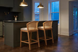 Two Lazise counter stools at a dark green island under brass pendant lights in a Toronto kitchen at dusk