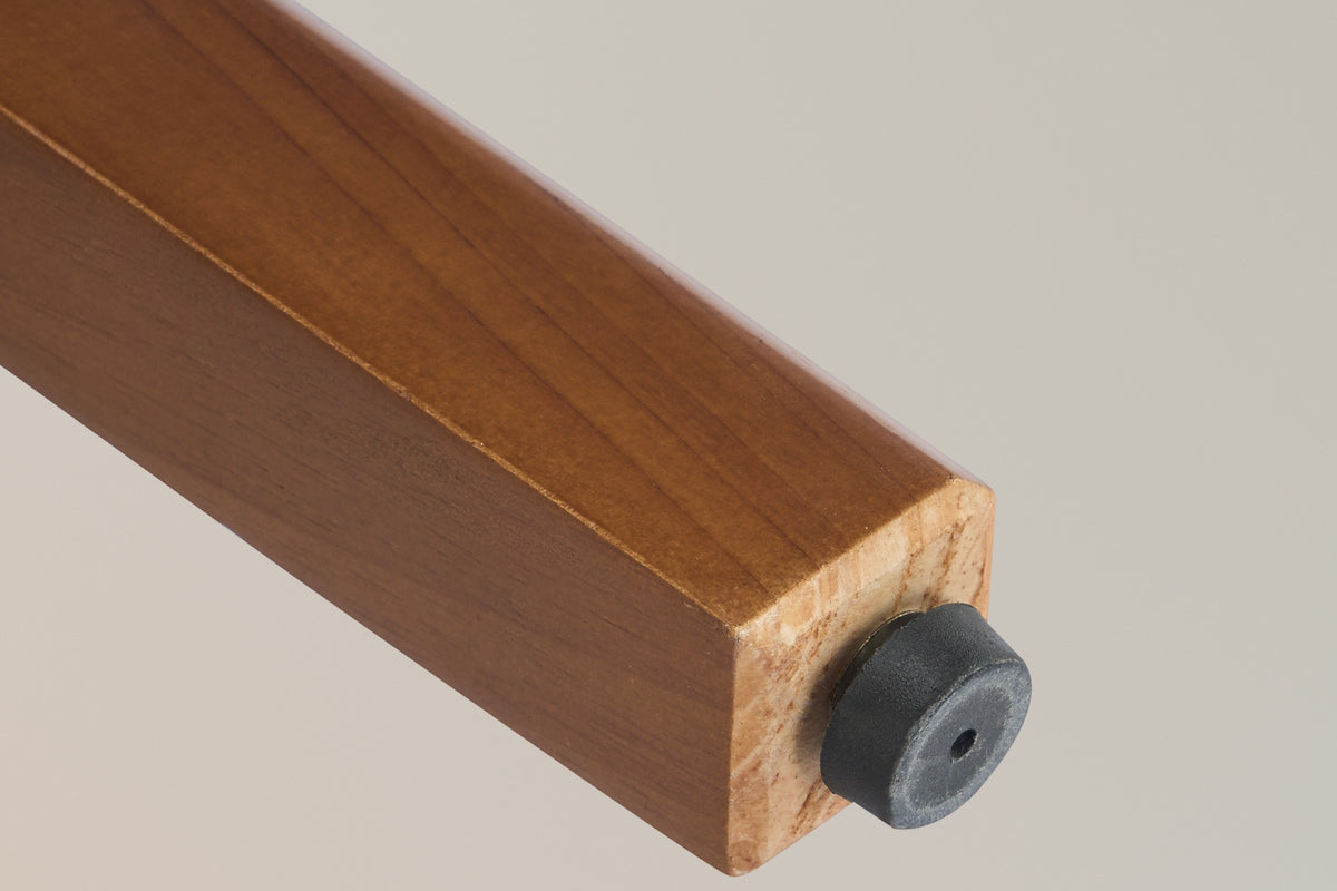 Close-up of a square walnut-finish leg of the Lazise stool, with its black non-slip foot cap