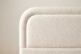 Close-up of the rounded headboard corner: a raised boucle border around the inset panel