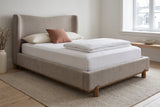 Lerma platform bed in dark beige with white linen and a terracotta cushion in a Quebec City bedroom