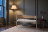 Levanto loveseat in beige boucle and natural ash against a green-grey panelled wall in a Toronto townhouse at dusk, a brass floor lamp lit beside it