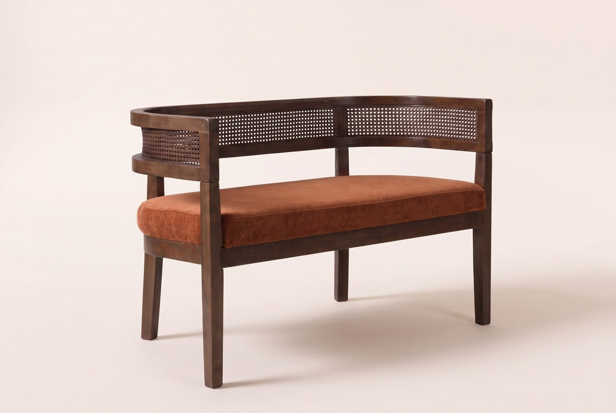 Levanto cane-back loveseat in dark orange fabric on a walnut-finish rubberwood frame, three-quarter view on a warm cream studio backdrop