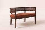 Levanto cane-back loveseat in dark orange fabric on a walnut-finish rubberwood frame, three-quarter view on a warm cream studio backdrop