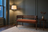 Levanto loveseat against a green-grey panelled wall in a Toronto townhouse at dusk, a brass floor lamp lit beside it