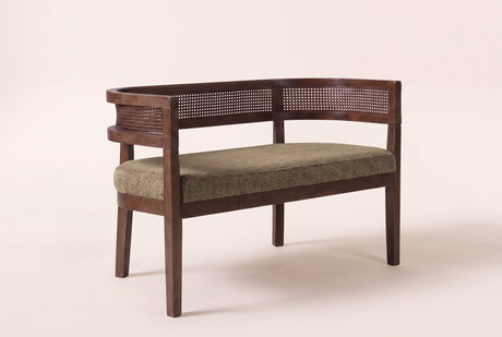 Levanto cane-back loveseat in green fabric on a walnut-finish rubberwood frame, three-quarter view on a warm cream studio backdrop