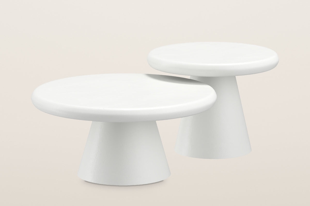 Levico nesting coffee tables in matte white, a large low table and a small taller one, each on a cone base, on a warm light studio backdrop