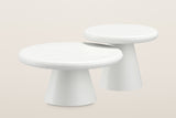 Levico nesting coffee tables in matte white, a large low table and a small taller one, each on a cone base, on a warm light studio backdrop
