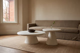 Levico white nesting coffee tables in front of a taupe linen sofa in an oatmeal plaster Toronto living room, a brown bowl on the large top