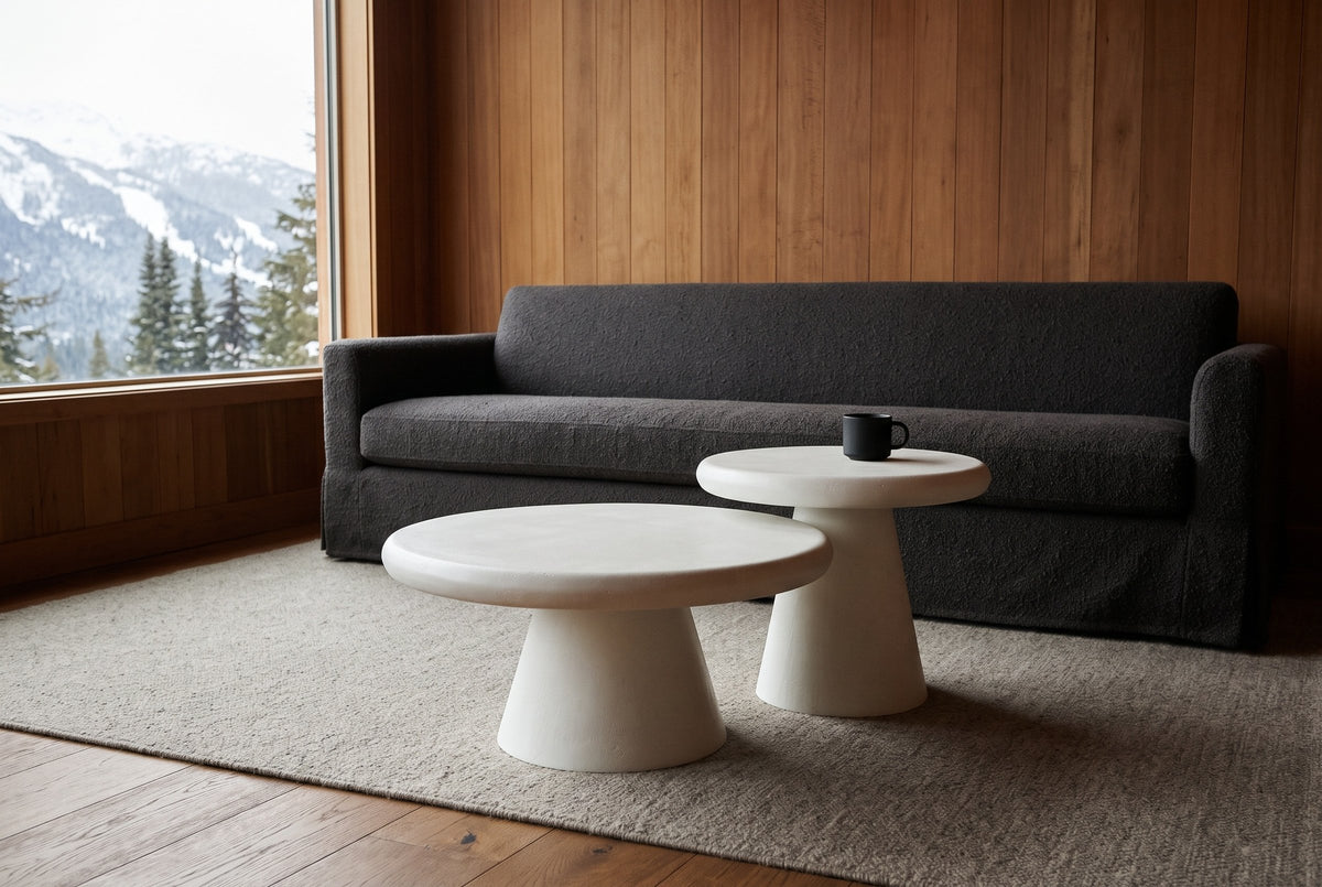Levico white nesting coffee tables in front of a charcoal boucle sofa in a cedar-panelled Whistler chalet, snowy slopes through the window
