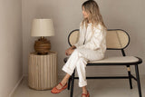 Linden table lamp on a wooden side table beside a cane bench