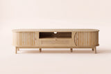 The Livia media console in Natural seen straight on, with its two reeded doors, open shelf and rattan drawer